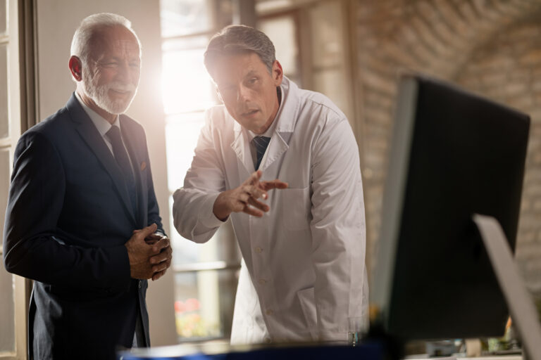 mid adult doctor explaining mature businessman medical data computer clinic